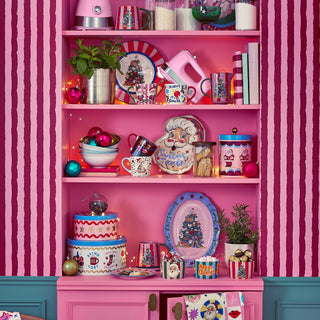 Colorful kitchen interior with pink shelves and cabinets, decorated with various items against a pink striped wall.